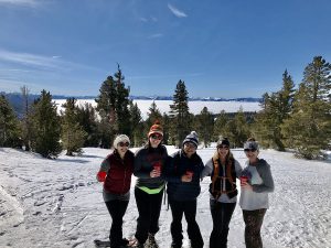 women smiling with snowshoes on